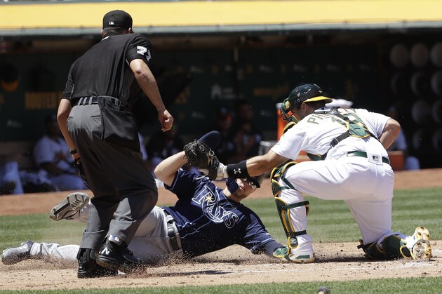 Oakland Athletics catcher Josh Phegley, right, tags out Tampa Bay Rays' Austin Meadows, center, at home as umpire Jim Reynolds (77) watches during the third inning of a baseball game in Oakland, Calif., Sunday, June 23, 2019. (AP Photo/Jeff Chiu)