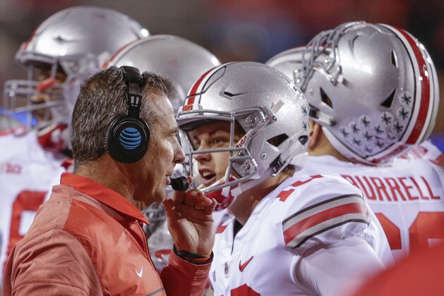 Ohio State head coach Urban Meyer talks to on his headset as quarterback Joe Burrow (10) talks to a different person, during a time out in the second half of an NCAA college football game against Nebraska in Lincoln, Neb., Saturday, Oct. 14, 2017. Ohio State won 56-14. (AP Photo/Nati Harnik)