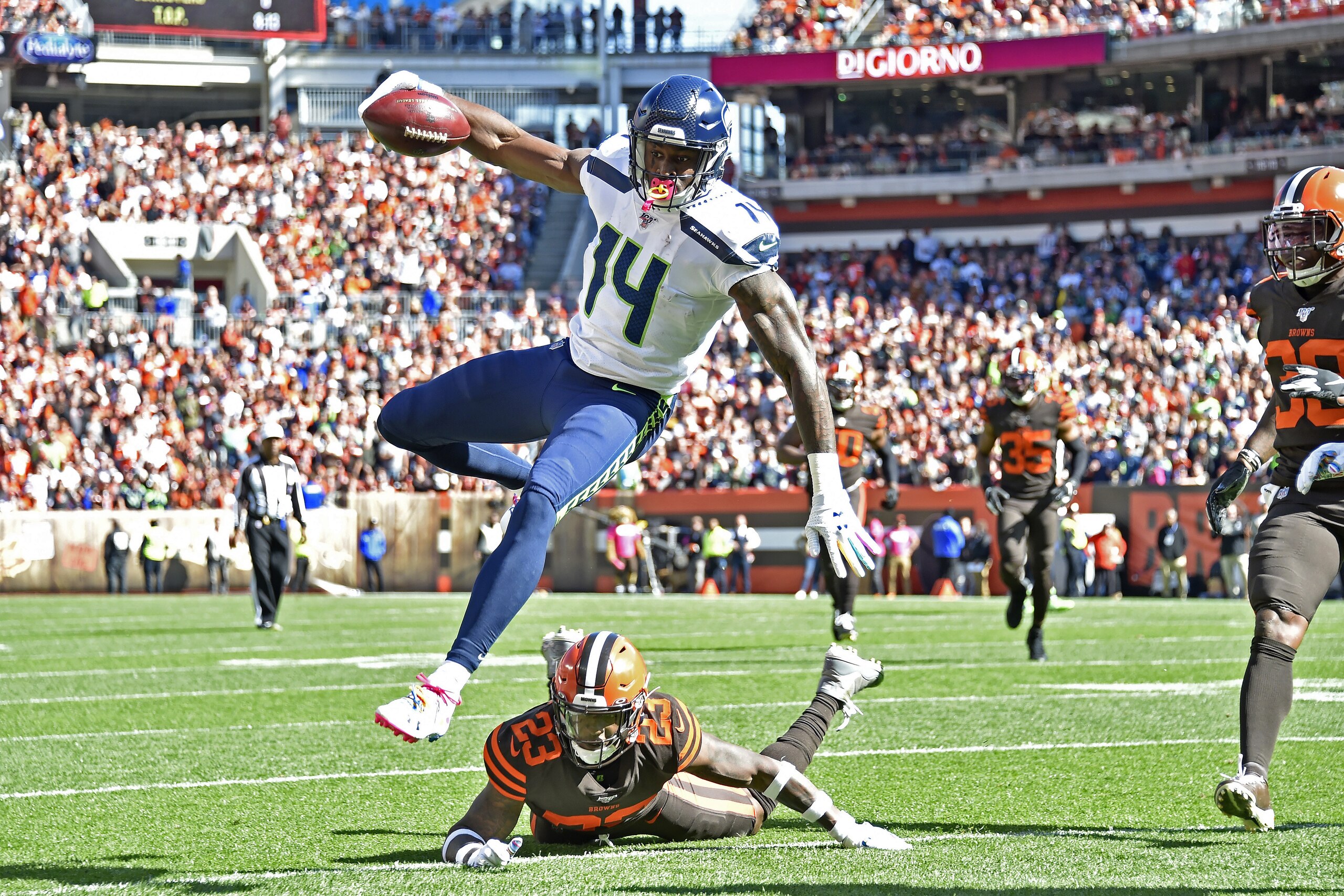 CLEVELAND, OHIO - OCTOBER 13: D.K. Metcalf #14 of the Seattle Seahawks leaps over Damarious Randall #23 of the Cleveland Browns or extra yards during the second quarter at FirstEnergy Stadium on October 13, 2019 in Cleveland, Ohio. (Photo by Jason Miller/Getty Images)