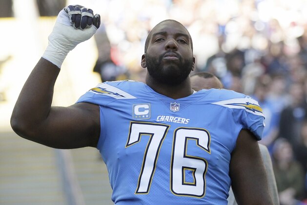 FILE - In this Oct. 21, 2018, file photo, Los Angeles Chargers offensive tackle Russell Okung (76) raises his first as the national anthem is played before an NFL football game against Tennessee Titans at Wembley stadium in London. Chargers offensive lineman Russell Okung will miss most of training camp due to blood clots. The veteran left tackle revealed Thursday, July 25, 2019, on Twitter that he experienced chest pains during an offseason practice at the team facility in June. Okung said he went to an urgent care and that tests revealed he suffered a pulmonary embolism.(AP Photo/Tim Ireland, File)