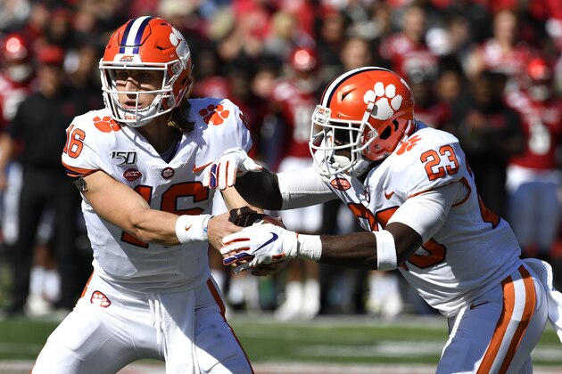 Clemson quarterback Trevor Lawrence (16) hands the ball off to running back Lyn-J Dixon (23) during the first half of an NCAA college football game against Louisville in Louisville, Ky., Saturday, Oct. 19, 2019. (AP Photo/Timothy D. Easley)
