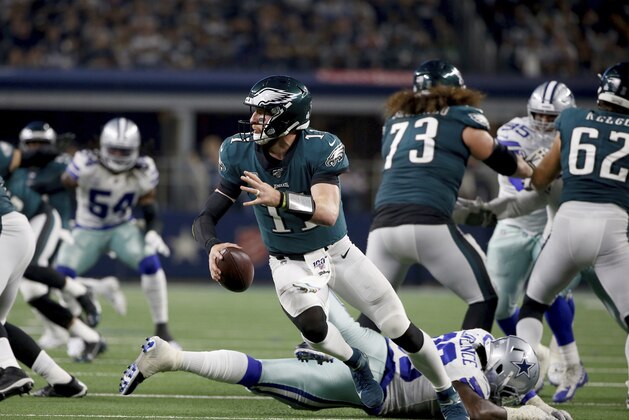 Philadelphia Eagles quarterback Carson Wentz (11) escapes pressure from Dallas Cowboys defensive end Demarcus Lawrence, bottom rear, in the second half of an NFL football game in Arlington, Texas, Sunday, Oct. 20, 2019. (AP Photo/Ron Jenkins)