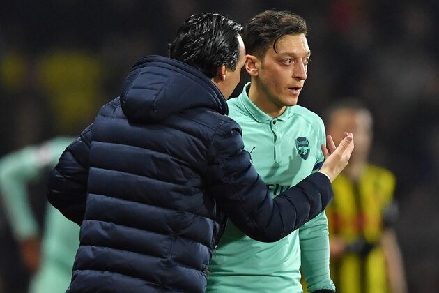 Arsenal's Spanish head coach Unai Emery (L) talks with Arsenal's German midfielder Mesut Ozil (R) during the English Premier League football match between Watford and Arsenal at Vicarage Road Stadium in Watford, north of London on April 15, 2019. (Photo by Ben STANSALL / AFP) / RESTRICTED TO EDITORIAL USE. No use with unauthorized audio, video, data, fixture lists, club/league logos or 'live' services. Online in-match use limited to 120 images. An additional 40 images may be used in extra time. No video emulation. Social media in-match use limited to 120 images. An additional 40 images may be used in extra time. No use in betting publications, games or single club/league/player publications. /         (Photo credit should read BEN STANSALL/AFP/Getty Images)