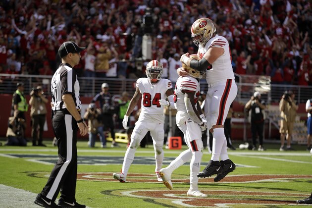 San Francisco 49ers running back Tevin Coleman is greeted by teammate offensive guard Mike Person, top, after scoring a touchdown during the first half of an NFL football game against the Carolina Panthers in Santa Clara, Calif., Sunday, Oct. 27, 2019. In the background is San Francisco 49ers wide receiver Kendrick Bourne (84). (AP Photo/Ben Margot)