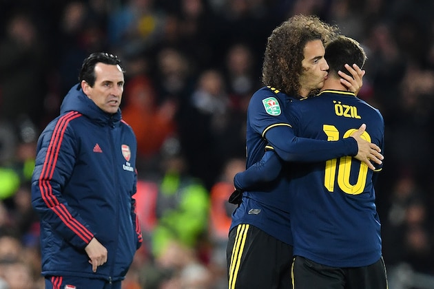 Arsenal's Spanish head coach Unai Emery (L) watches as Arsenal's German midfielder Mesut Ozil leaves the pitch after being substituted off for Arsenal's French midfielder Matteo Guendouzi during the English League Cup fourth round football match between Liverpool and Arsenal at Anfield in Liverpool, north west England on October 30, 2019. (Photo by Paul ELLIS / AFP) / RESTRICTED TO EDITORIAL USE. No use with unauthorized audio, video, data, fixture lists, club/league logos or 'live' services. Online in-match use limited to 75 images, no video emulation. No use in betting, games or single club/league/player publications. /  (Photo by PAUL ELLIS/AFP via Getty Images)