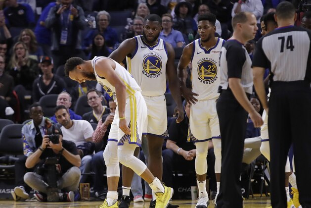 Golden State Warriors' Stephen Curry, left, grimaces after Phoenix Suns' Aron Baynes fell onto him during the second half of an NBA basketball game Wednesday, Oct. 30, 2019, in San Francisco. Curry left the game. (AP Photo/Ben Margot)