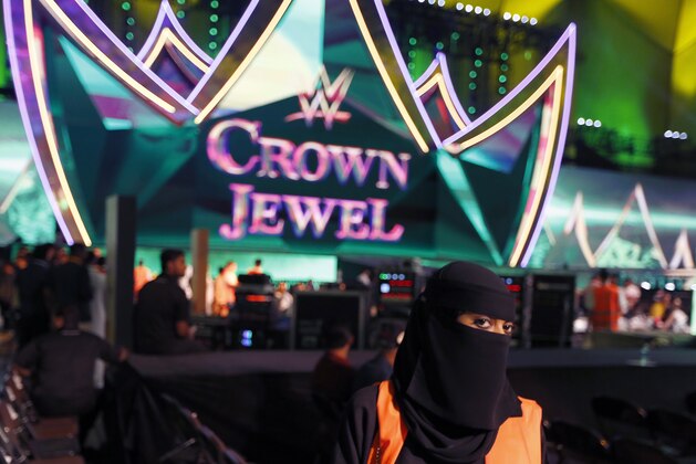 A Saudi women wait to clear seats of wrestling fans during the World Wrestling Entertainment