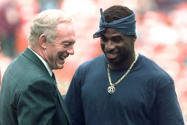 Dallas Cowboys owner Jerry Jones talks with his newest acquisition, Deion Sanders, on the sidelines before the start of the Cowboys game against the Washington Redskins at RFK Stadium in Washington Sunday, Oct. 1, 1995. Sanders, who underwent ankle surgery earlier this week, hopes to be in uniform  in two weeks. (AP Photo/Doug Mills)