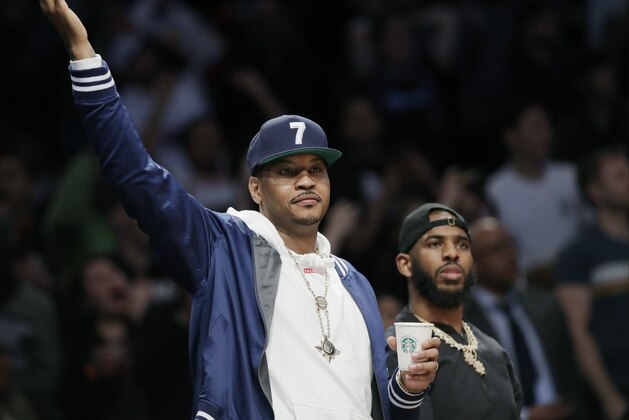 Former NBA player Carmelo Anthony gestures as he and Houston Rockets guard Chris Paul watch Miami Heat guard Dwyane Wade during the second half of an NBA basketball game, Wednesday, April 10, 2019, in New York. (AP Photo/Kathy Willens)