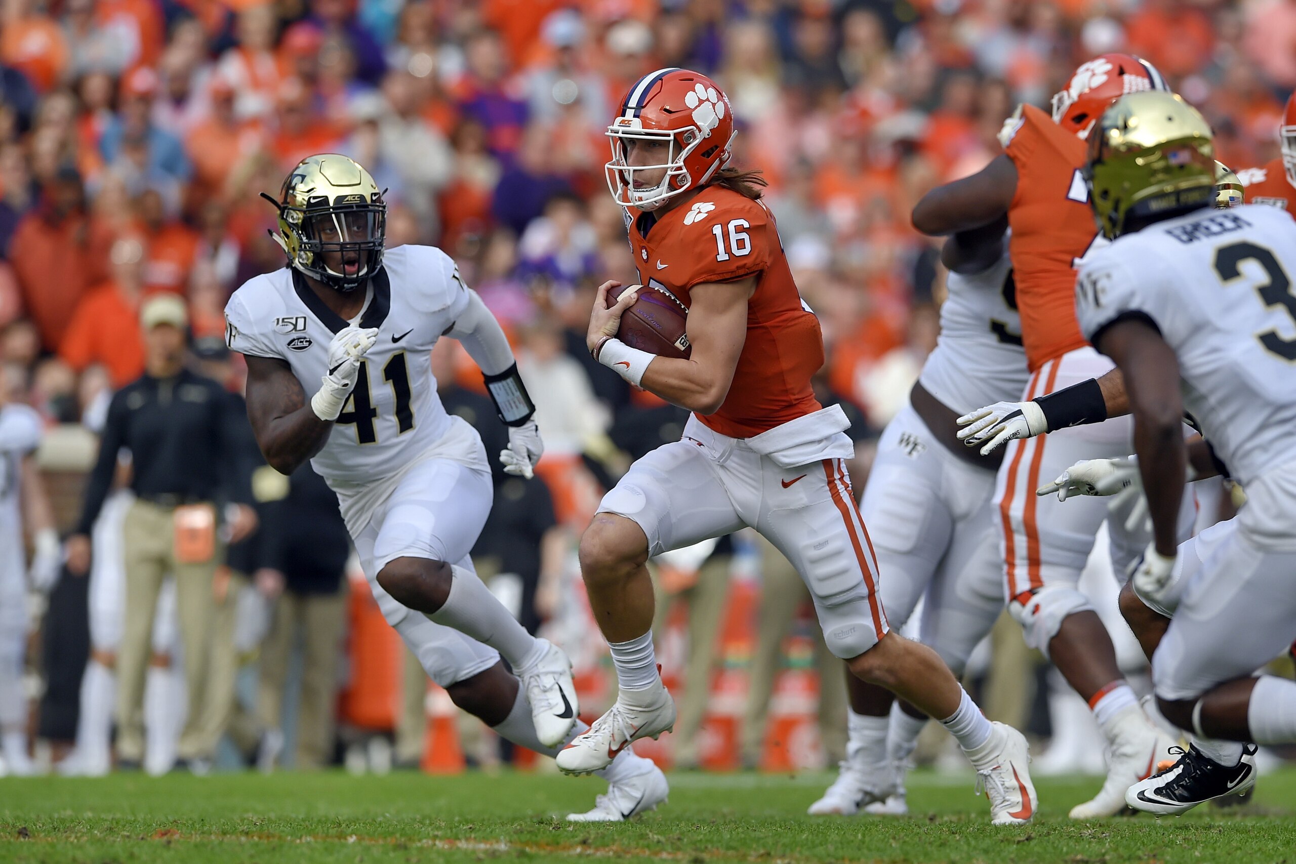 Clemson quarterback Trevor Lawrence (16) scrambles out of the pocket while defended by Wake Forest's Ja'Corey Johns (41) Clemson's during the first half of an NCAA college football game Saturday, Nov. 16, 2019, in Clemson, S.C. (AP Photo/Richard Shiro)