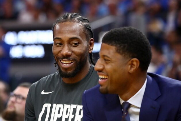 SAN FRANCISCO, CALIFORNIA - OCTOBER 24:   Kawhi Leonard #2 and Paul George #13 of the LA Clippers smile while sitting on the bench during their game against the Golden State Warriors at Chase Center on October 24, 2019 in San Francisco, California.  NOTE TO USER: User expressly acknowledges and agrees that, by downloading and or using this photograph, User is consenting to the terms and conditions of the Getty Images License Agreement. (Photo by Ezra Shaw/Getty Images)