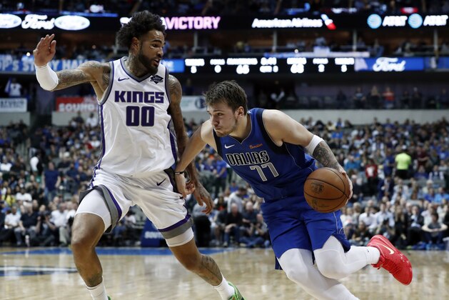 Sacramento Kings' Willie Cauley-Stein (00) defends as Dallas Mavericks' Luka Doncic (77) works to the basket during an NBA basketball game in Dallas, Tuesday, March 26, 2019. (AP Photo/Tony Gutierrez)
