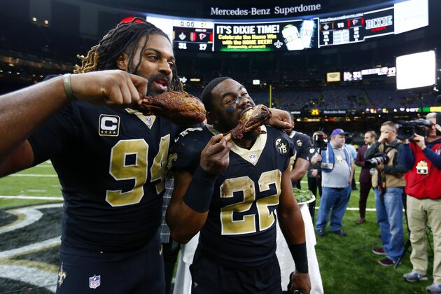 New Orleans Saints defensive end Cameron Jordan (94) and New Orleans Saints running back Mark Ingram (22) eat turkey drumsticks after their Thanksgiving night NFL football game against the Atlanta Falcons in New Orleans, Thursday, Nov. 22, 2018. The Saints won 31-17. (AP Photo/Butch Dill)