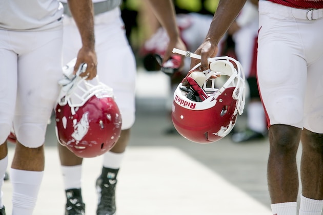 Two Arkansas defensive players walk onto the field holding their helmets before a preseason NCAA college football practice at Donald W. Reynolds Razorback Stadium in Fayetteville, Ark., Saturday, Aug. 16, 2014.  (AP Photo/Gareth Patterson)