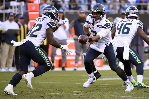 Seattle Seahawks quarterback Russell Wilson (3) hands pff to running back Chris Carson (32) during the second half of an NFL football game against the Carolina Panthers in Charlotte, N.C., Sunday, Dec. 15, 2019. (AP Photo/Mike McCarn)