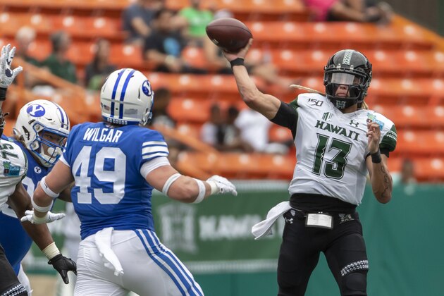 Hawaii quarterback Cole McDonald (13) throws a pass as BYU linebacker Payton Wilgar (49) watches during the first half of the Hawaii Bowl NCAA college football game Tuesday, Dec. 24, 2019, in Honolulu. (AP Photo/Eugene Tanner)