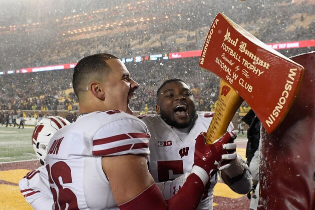 MINNEAPOLIS, MINNESOTA - NOVEMBER 30: Zack Baun #56 and Chris Orr #54 of the Wisconsin Badgers grab the Paul Bunyan Football Trophy after defeating the Minnesota Golden Gophers in the game at TCF Bank Stadium on November 30, 2019 in Minneapolis, Minnesota. The Badgers defeated the Golden Gophers 38-17. (Photo by Hannah Foslien/Getty Images)