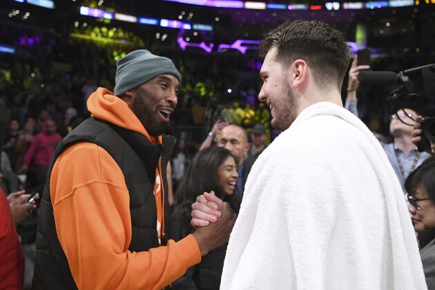 CORRECTS THE SCORE TO 95 - Former Los Angeles Laker Kobe Bryant, left, greets Dallas Mavericks guard Luka Doncic after an NBA basketball game Sunday, Dec. 29, 2019, in Los Angeles. The Lakers won 108-95. (AP Photo/Michael Owen Baker)