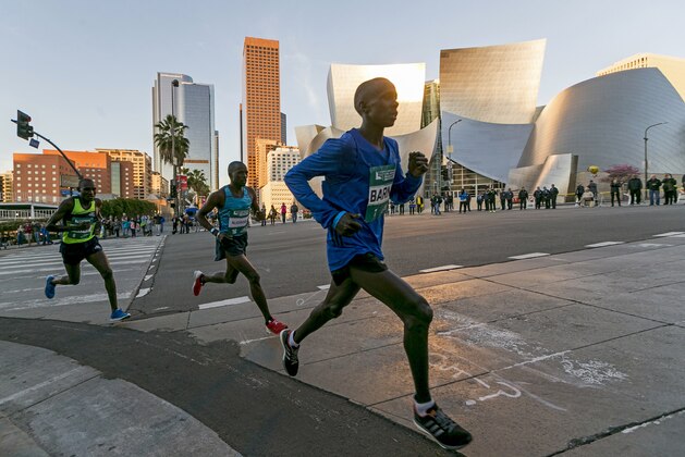 Los Angeles Marathon Elite runners, from left, Weldon Kirui, Simon Njoroge, Elisha Barno race past the Walt Disney Concert Hall in Los Angeles Sunday, March 18, 2018. Kirui won the Los Angeles Marathon with an unofficial time of 2 hours 11 minutes and 47 seconds. (AP Photo/Damian Dovarganes)