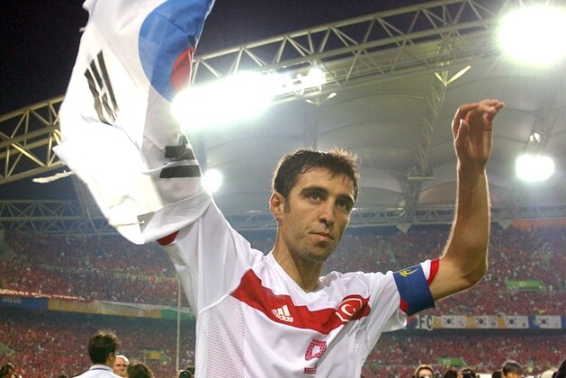 FILE - In this Saturday, June 29, 2002, file photo, Turkey's Hakan Sukur holds a South Korean flag at the end of the 2002 World Cup third place playoff soccer match between South Korea and Turkey, at the Daegu World Cup stadium, in Daegu, South Korea.  Turkey's state-run news agency reports Friday, Aug. 12, 2016, authorities have issued an arrest warrant for former soccer star and legislator Hakan Sukur over his alleged links to a U.S.-based Muslim cleric, accused by Turkey of masterminding last month's failed coup. (AP Photo/Vincent Yu, FILE)