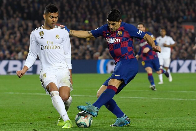 TOPSHOT - Real Madrid's Brazilian midfielder Casemiro (L) challenges Barcelona's Uruguayan forward Luis Suarez during the