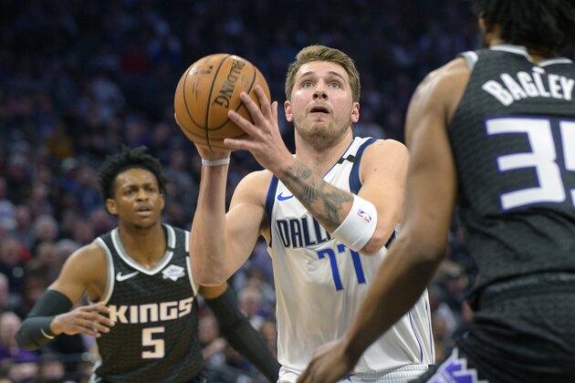 Dallas Mavericks forward Luka Doncic (77) drives to the basket past Sacramento Kings guard De'Aaron Fox (5) and forward Marvin Bagley III (35) during the first quarter of an NBA basketball game in Sacramento, Calif., Wednesday, Jan. 15, 2020. (AP Photo/Randall Benton)