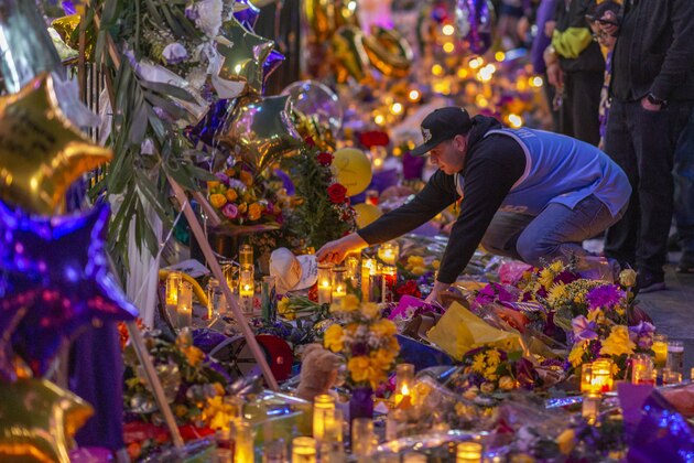 LOS ANGELES, CA - JANUARY 28: A man places a hat at a makeshift memorial near Staples Center in remembrance of former NBA great Kobe Bryant who, along with his 13-year-old daughter Gianna, died January 26 in a helicopter crash, on January 28, 2020 in Los Angeles, California. Kobe and