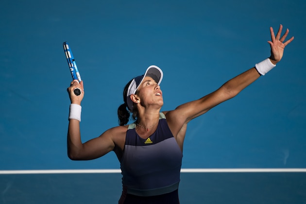 MELBOURNE, AUSTRALIA - JANUARY 30: Garbine Muguruza of Spain serves in her semi-final match against Simona Halep of Romania on day eleven of the 2020 Australian Open at Melbourne Park on January 30, 2020 in Melbourne, Australia. (Photo by TPN/Getty Images)