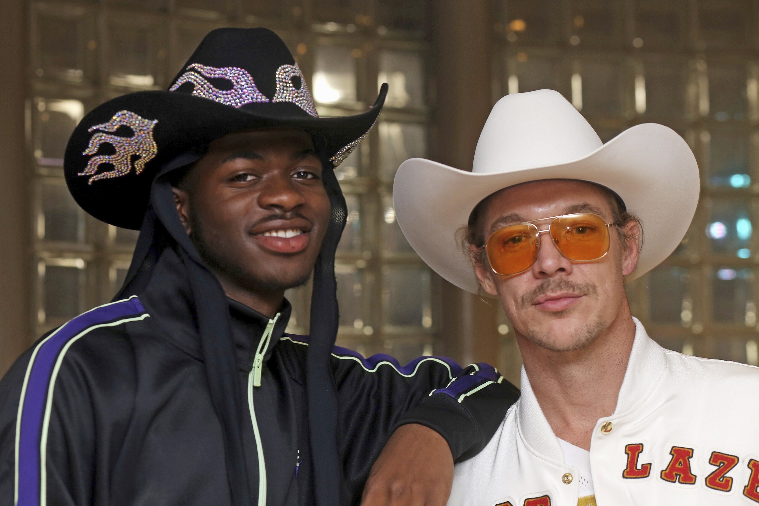 Grammy-winning recording artists Lil Nas X, left, and Diplo pose for a photograph at the NFL Super Bowl 54 football game in Miami Gardens, Fla., Sunday, Feb. 2, 2020. DJ-producer Diplo and rapper Lil Nas X, who stars in a Super Bowl commercial for Doritos, chatted in a suite at Hard Rock Stadium while watching the game. The pair, both sporting large cowboy hats Sunday, collaborated on a remix of â€œOld Town Road,