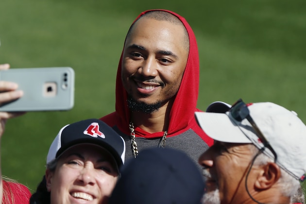 Boston Red Sox's Mookie Betts takes a selfie with fans on the warning track before a baseball game against the Baltimore Orioles in Boston, Sunday, Sept. 29, 2019. (AP Photo/Michael Dwyer)