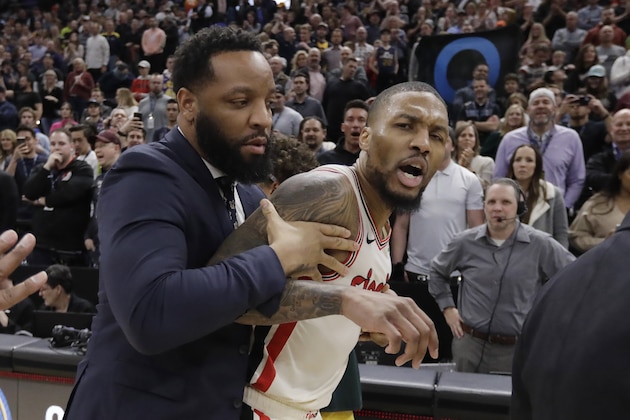 Portland Trail Blazers guard Damian Lillard (0) is held back following the team's NBA basketball game against the Utah Jazz of Friday Feb. 7, 2020, in Salt Lake City. The Jazz won 117-114. (AP Photo/Rick Bowmer)