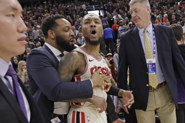 Portland Trail Blazers guard Damian Lillard (0) is held back following the team's NBA basketball game against the Utah Jazz on Friday, Feb. 7, 2020, in Salt Lake City. The Jazz won 117-114. (AP Photo/Rick Bowmer)