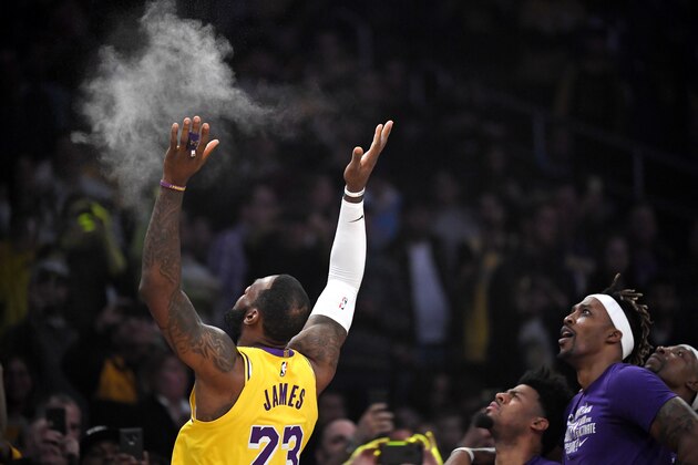 Los Angeles Lakers forward LeBron James, left, tosses powder in the air as teammates watch prior to an NBA basketball game against the Phoenix Suns Monday, Feb. 10, 2020, in Los Angeles. (AP Photo/Mark J. Terrill)