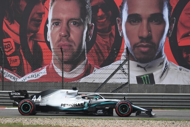 Mercedes' British driver Lewis Hamilton steers his car past a billboard featuring portraits of himself (R) and Ferrari's German driver Sebastian Vettel during the first practice session for the Formula One Chinese Grand Prix in Shanghai on April 12, 2019. (Photo by GREG BAKER / AFP)        (Photo credit should read GREG BAKER/AFP via Getty Images)