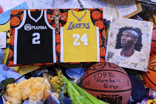 Memorabilia for NBA star Kobe Bryant are placed at a memorial for Bryant while fans gather to pay their respect near Staples Center in Los Angeles Sunday, Feb. 2, 2020. Bryant, the 18-time NBA All-Star who won five championships and became one of the greatest basketball players of his generation during a 20-year career with the Lakers, died in a helicopter crash Sunday, Jan. 26. (AP Photo/Damian Dovarganes)