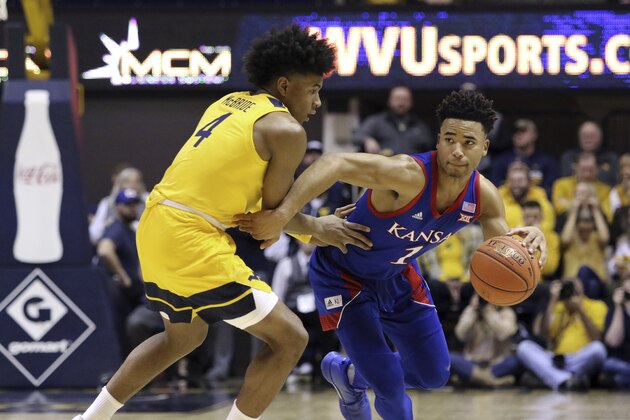 Kansas guard Devon Dotson (1) is defended by West Virginia guard Miles McBride (4) during the first half of an NCAA college basketball game Wednesday, Feb. 12, 2020, in Morgantown, W.Va. (AP Photo/Kathleen Batten)