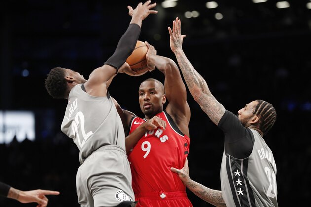 Brooklyn Nets guard Caris LeVert (22) and Nets forward Wilson Chandler (21) defend Toronto Raptors center Serge Ibaka (9) during the first quarter of an NBA basketball game, Wednesday, Feb. 12, 2020, in New York. (AP Photo/Kathy Willens)