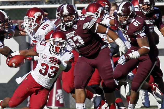 Arkansas running back Dennis Johnson (33) runs away from Mississippi State defensive linemen P.J. Jones (93) and Preston Smith (91) in the third quarter of an NCAA college football game in Starkville, Miss., Saturday, Nov. 17, 2012.  Mississippi State won 45-14. (AP Photo/Rogelio V. Solis)