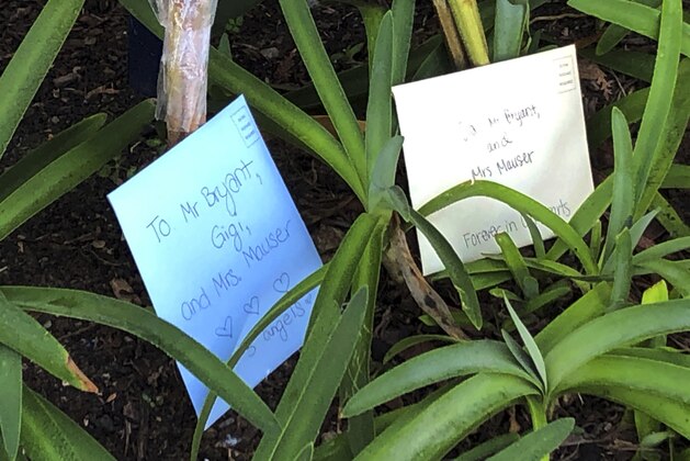 Flowers and messages are placed in front of Harbor Day School, a private elementary school in Corona Del Mar, Calif., Monday, Jan. 27, 2020. Christina Mauser, a girls basketball coach at the school, was among those killed in the helicopter crash that took the lives of former Lakers star Kobe Bryant and seven others Sunday. (AP Photo/Amy Taxin)