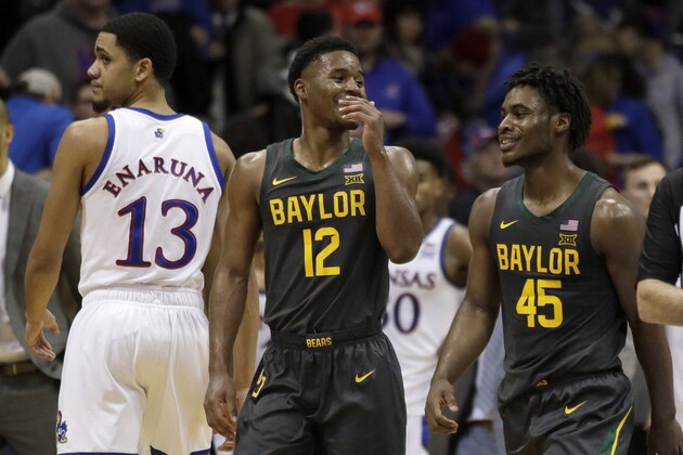 Baylor guard Jared Butler (12) smiles with teammate Davion Mitchell (45) while walking past Kansas guard Tristan Enaruna (13) following an NCAA college basketball game against Kansas in Lawrence, Kan., Saturday, Jan. 11, 2020. Baylor defeated Kansas 55-67. (AP Photo/Orlin Wagner)