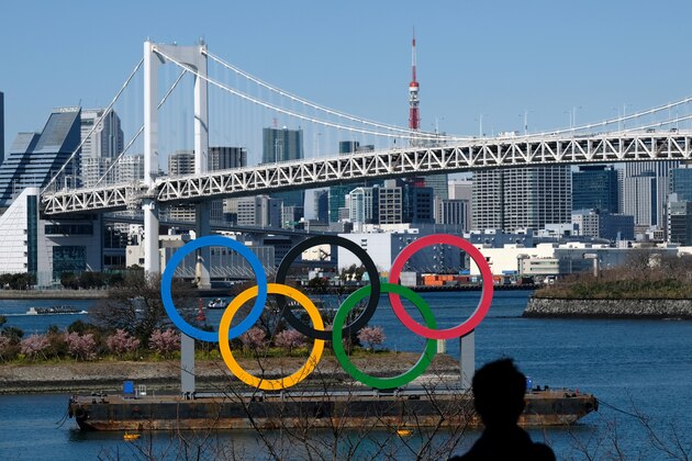 A man looks at an Olympic rings display installed off the shore of the Odaiba Marine Park in Tokyo on February 28, 2020. - The International Olympic Committee is