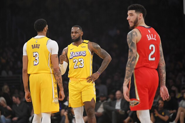 Los Angeles Lakers forward Anthony Davis, left, talks with forward LeBron James, center, as New Orleans Pelicans guard Lonzo Ball walks nearby during the first half of an NBA basketball game Friday, Jan. 3, 2020, in Los Angeles. (AP Photo/Mark J. Terrill)