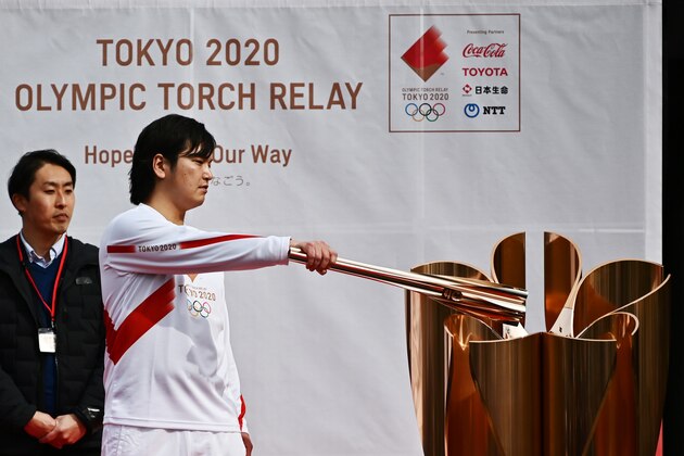 A runner holding an Olympic torch practices lighting a cauldron during a rehearsal of the Tokyo 2020 Olympics torch relay in Tokyo on February 15, 2020. (Photo by CHARLY TRIBALLEAU / AFP) (Photo by CHARLY TRIBALLEAU/AFP via Getty Images)