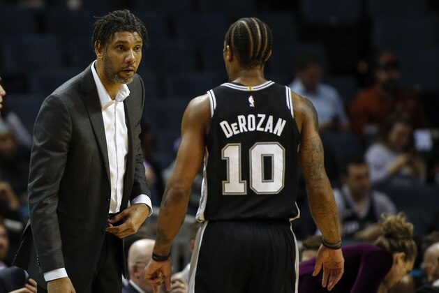 San Antonio Spurs acting head coach Tim Duncan, left, talks to San Antonio Spurs forward DeMar DeRozan in the first half of an NBA basketball game against the Charlotte Hornets in Charlotte, N.C., Tuesday, March 3, 2020. (AP Photo/Nell Redmond)
