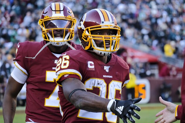 Washington Redskins running back Adrian Peterson (26) is greeted by teammates on sidelines after scoring a touchdown against the Philadelphia Eagles in the second half of an NFL football game, Sunday, Dec. 15, 2019, in Landover, Md. Running behind Peterson is Washington Redskins quarterback Dwayne Haskins. (AP Photo/Mark Tenally)