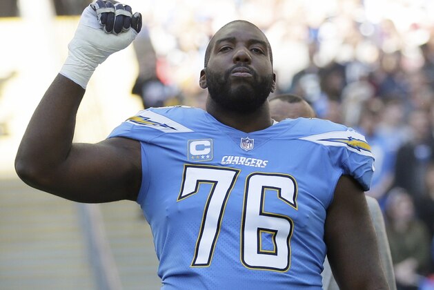 FILE - In this Oct. 21, 2018, file photo, Los Angeles Chargers offensive tackle Russell Okung (76) raises his first as the national anthem is played before an NFL football game against Tennessee Titans at Wembley stadium in London. Chargers offensive lineman Russell Okung will miss most of training camp due to blood clots. The veteran left tackle revealed Thursday, July 25, 2019, on Twitter that he experienced chest pains during an offseason practice at the team facility in June. Okung said he went to an urgent care and that tests revealed he suffered a pulmonary embolism.(AP Photo/Tim Ireland, File)