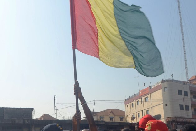 People wave a Guinean flag as they celebrate in the streets of Conakry after Guinea qualified for the Africa Cup of Nations quarter-finals on January 29, 2015, after a drawing of lots was required to separate them and Mali. Guinea and Mali were left to draw lots after they finished deadlocked on three points each behind winners the Ivory Coast in Group D. AFP PHOTO / BINANI        (Photo credit should read BINANI/AFP via Getty Images)