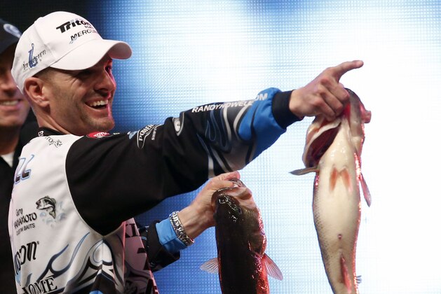Randy Howell, Springville, Ala., points to family and supporters as he holds up two bass at the weigh-in,  Sunday Feb. 23, 2014 in Birmingham, Ala. that helped him to win the Bassmaster Classic on Lake Guntersville. (AP Photo/Hal Yeager)