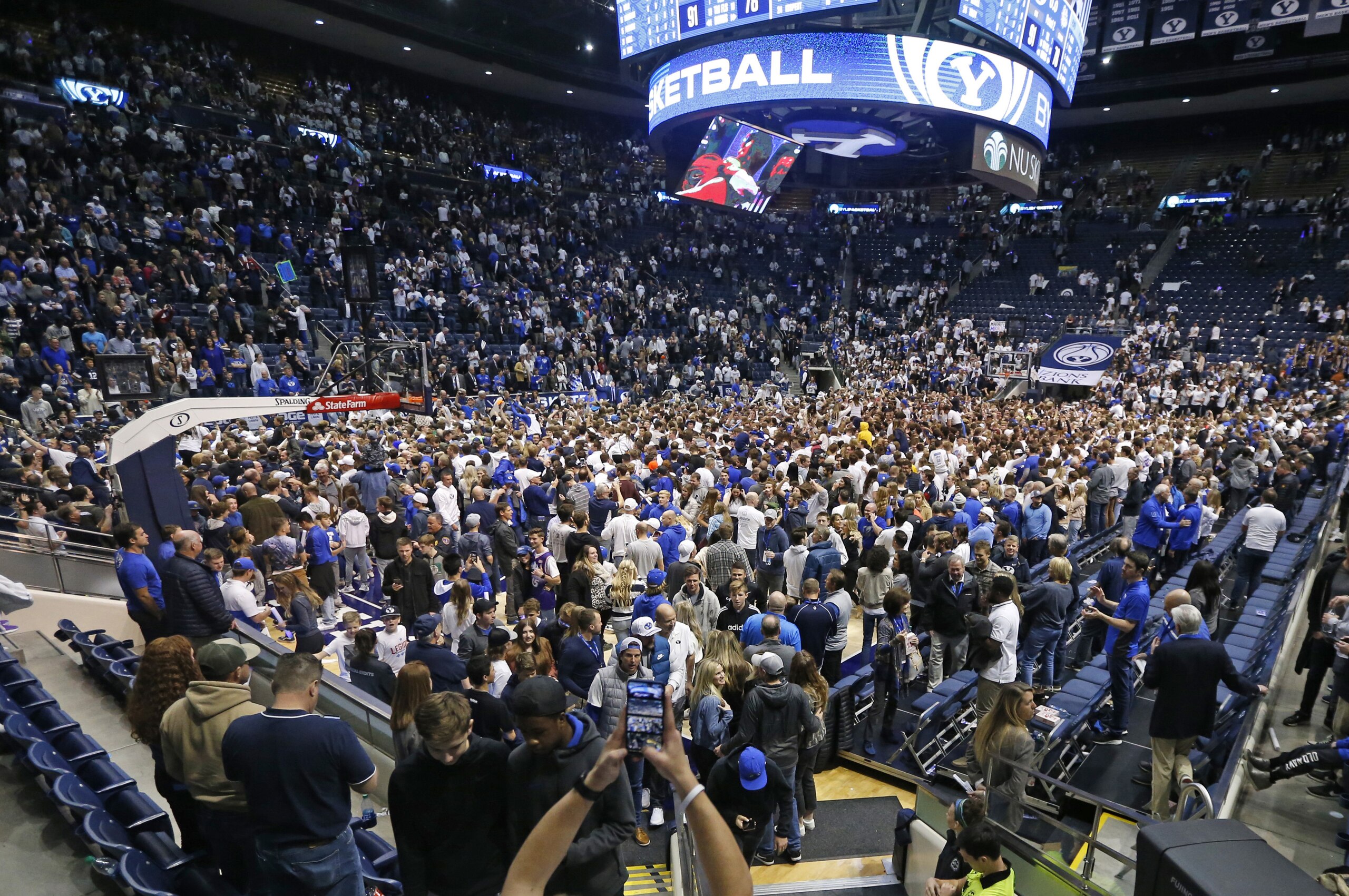 FILE - In this Feb. 22, 2020, file photo, BYU students and fans celebrate on the court following their victory over Gonzaga following an NCAA college basketball game, in Provo, Utah. Utah public health officials are contacting and testing BYU basketball fans who sat near a coronavirus patient at a game prior to the infection being diagnosed, the university said Monday, March 9, 2020. He had mild symptoms and there's little risk the virus was transmitted more widely the Feb. 22 game against Gonzaga, the school said in a statement. People who went to the game don't need to do anything unless the are contacted by the Utah County Health Department. (AP Photo/Rick Bowmer, File)