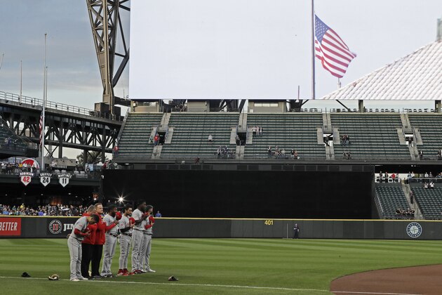 Cincinnati Reds players and coaches stand on the field at T-Mobile Park during a moment of remembrance for the victims of the Sept. 11, 2001, attacks, before the national anthem at the start of the team's baseball game against the Seattle Mariners, Wednesday, Sept. 11, 2019, in Seattle. (AP Photo/Ted S. Warren)
